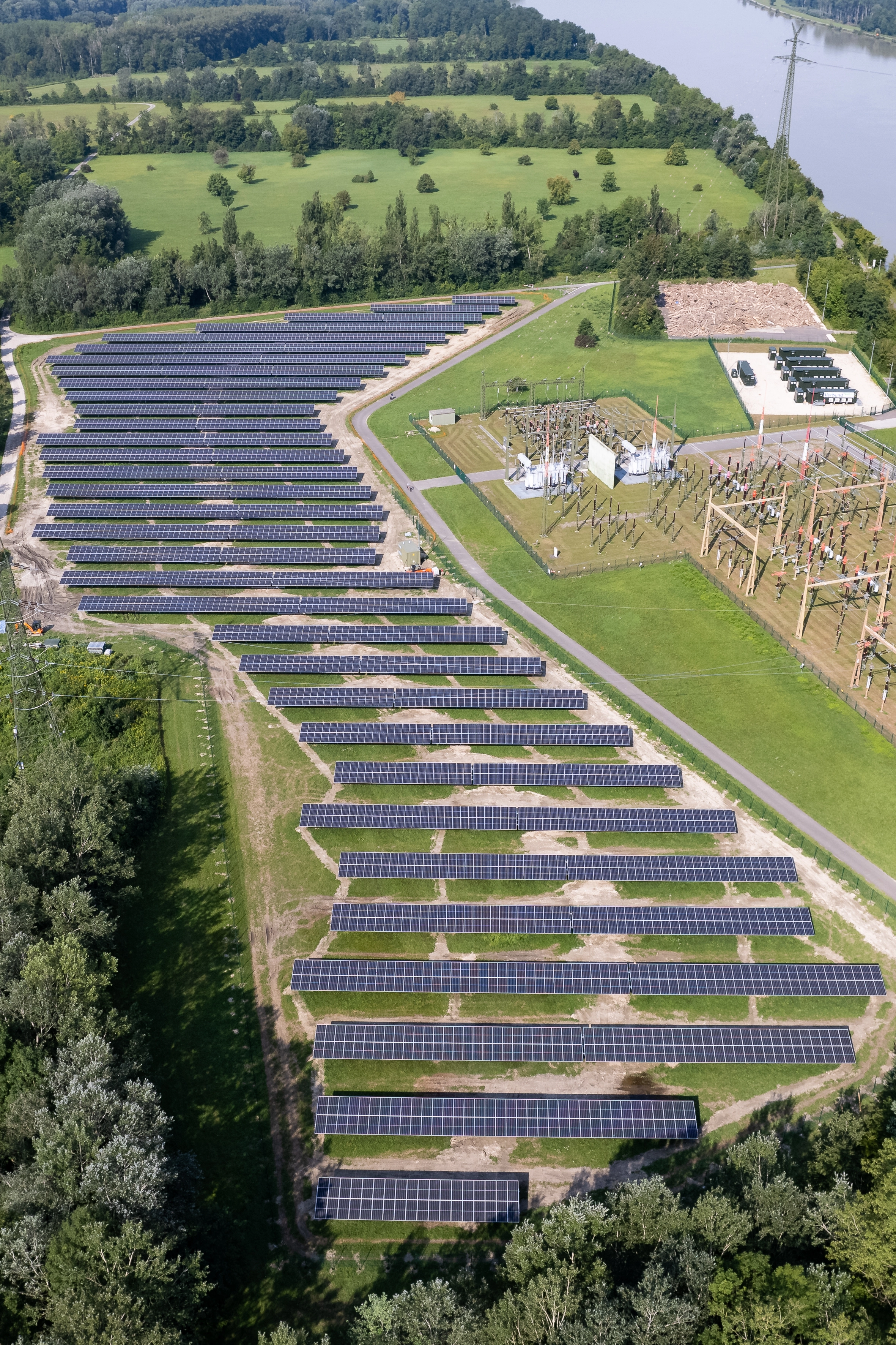 Wir blicken von auf die Photovoltaik-Paneele in Wallsee-Mitterkirchen. Auf der rechten Seite sehen wir die Umspannanlage und darüber die Blue Batterie. Die Sonne schein.